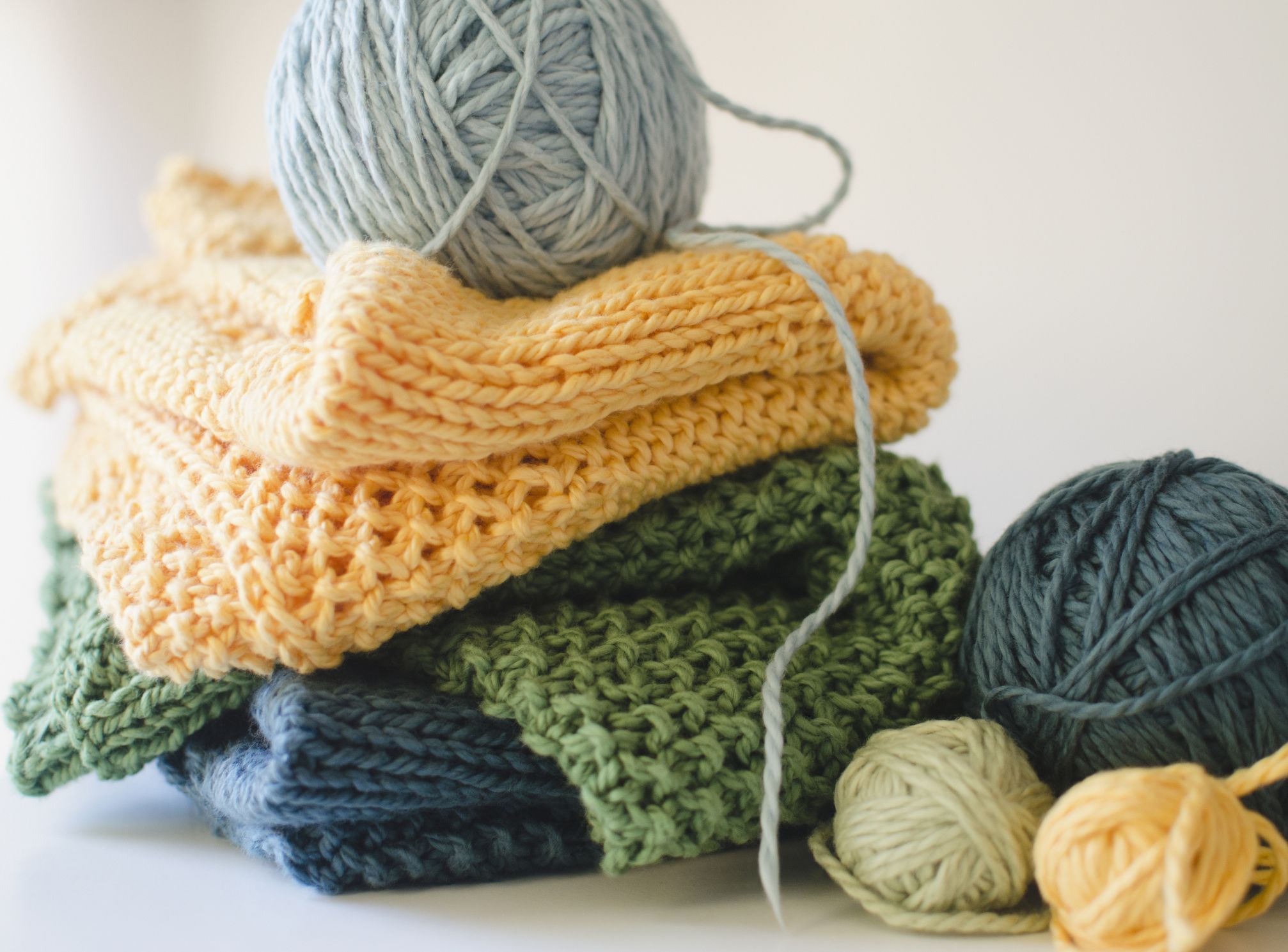 Stack of knitting samples with balls of yarn.