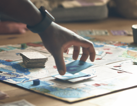 Image of table-top board game with hand placing cards