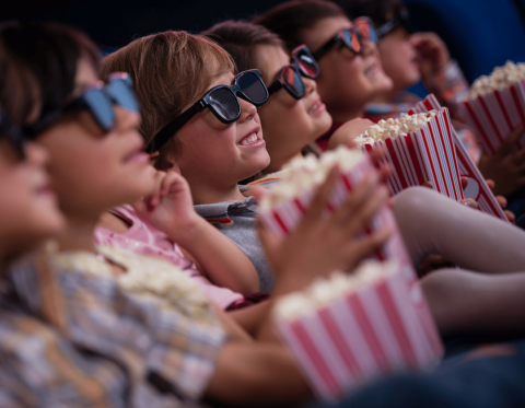 Row of children with boxes of popcorn watching a movie