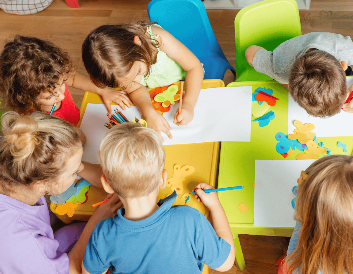 Group of young children at a table coloring on paper