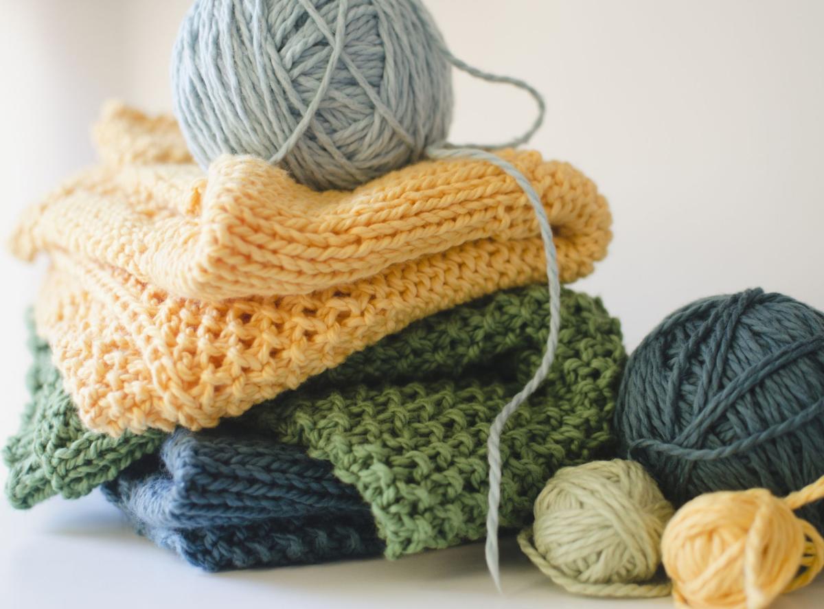 Stack of knitting samples with balls of yarn.
