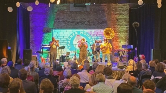 photo of band playing on stage to huge crowd in a small venu